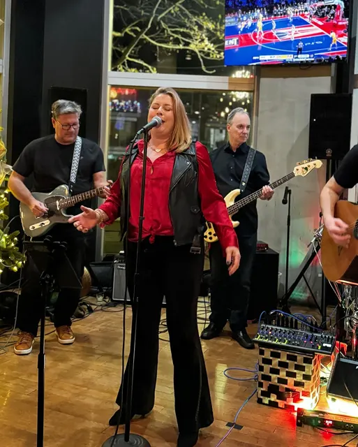 A singer in a red top out front of the band at Solace Outpost
