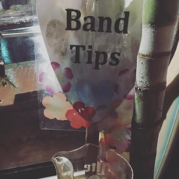 A Band Tips sign over a pitcher at a Clare and Don's show